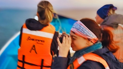 Three teen girls riding a motorboat in search of dolphins and whales to photograph