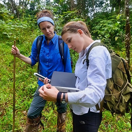 Two woman recording data collected in the forest.
