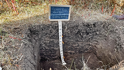 A freshly dug hole with a sign and measuring tape.