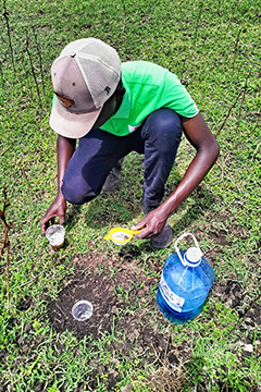 A man sitting on the grass testing soil for research purposes.