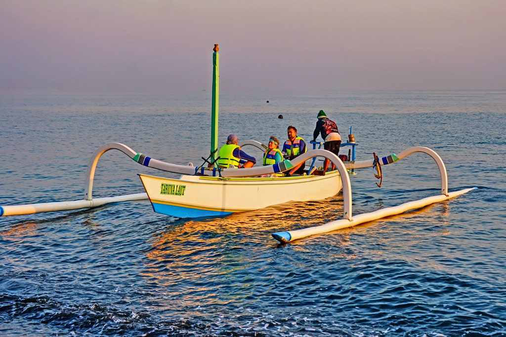 Group of scuba divers headed out to sea on small traditional Indonesian fishing boats