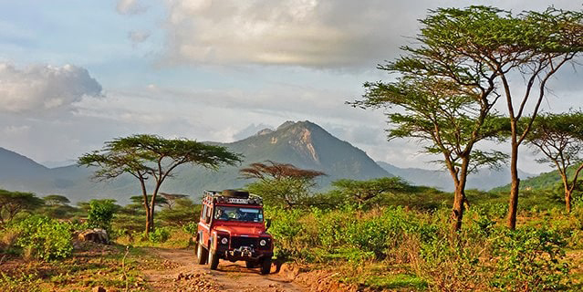 A red jeep driving through the mountains in Malawi.