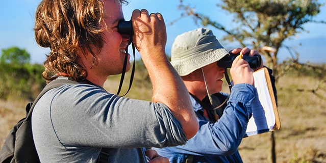 Two men looking through binoculars in Africa.
