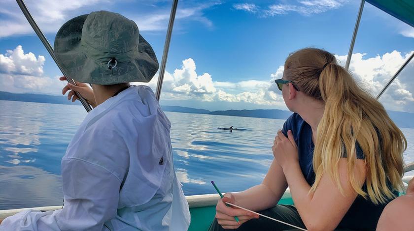 Two teen girls tracking a dolphin and recording the data in Costa Rica.