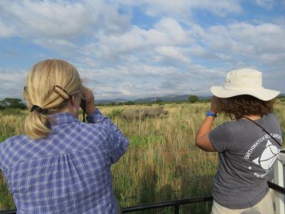 Two Earthwatch volunteers observe two rhinos (C) Lynne MacTavish