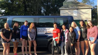 The 2019 Girls in Science Fellows standing in front of a WHOI bus