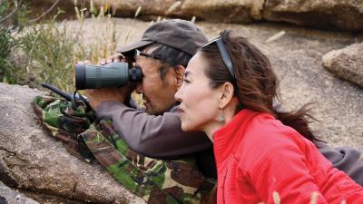 Earthwatch Lead Scientist Gana Wingard and another research use binoculars look for argali (Ovis ammon) (C) Earthwatch