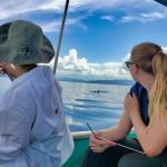 Two teen girls tracking a dolphin and recording the data in Costa Rica.
